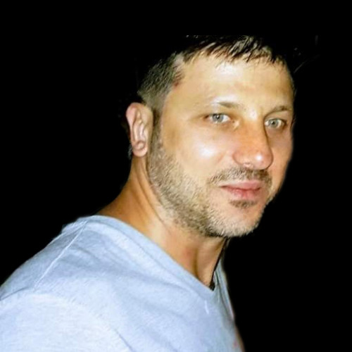 Mario Cezzare smiling in a blue shirt in front of the door